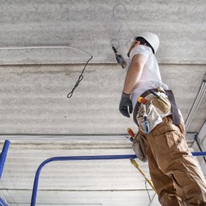 Electrician installer with a tool in his hands, working with cable on the construction site. Repair and handyman concept. House and house reconstruction.